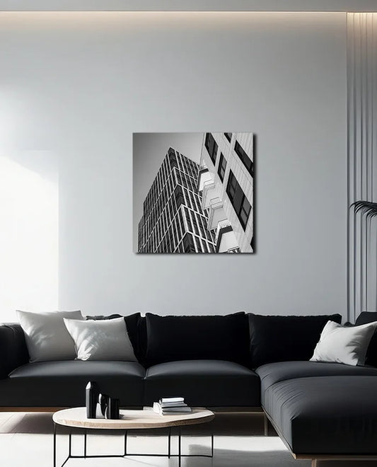 Schwarz weiß Fotografie moderner nach oben strebender Architektur geprägt von Linien und Kanten, an heller Wand hängend mit dunklem Sofa