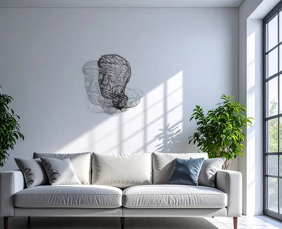 Der Kopf von Helmut Schmidt als Drahtskulptur mit Schatten von rechts, an heller wand hängend mit grauem Sofa