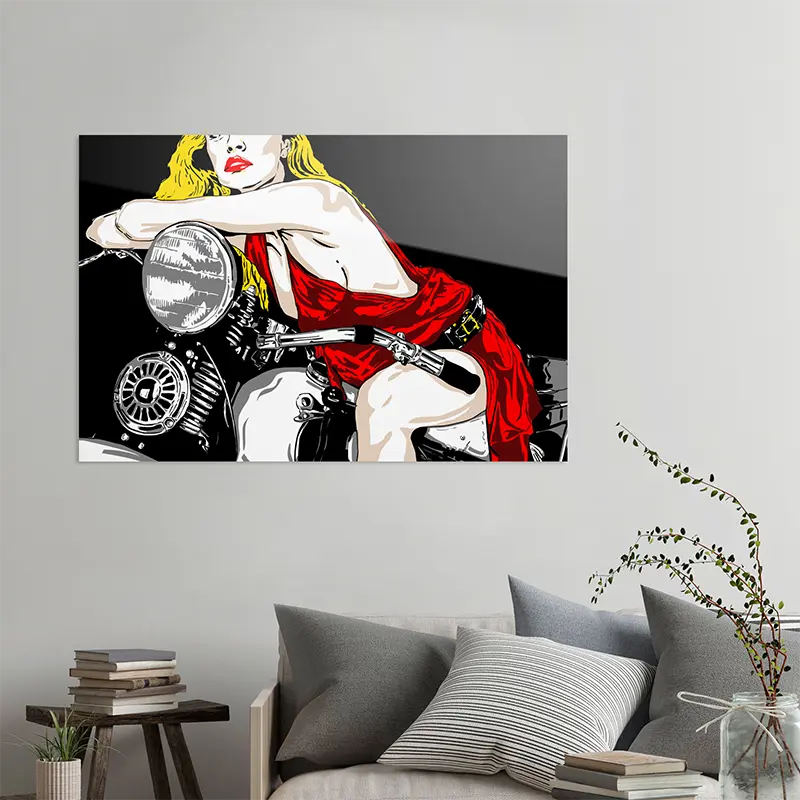 Eine Frau mit rotem Kleid und blonden Haaren sitzt auf einem Motorrad, an heller Wand hängend mit grauem Sofa