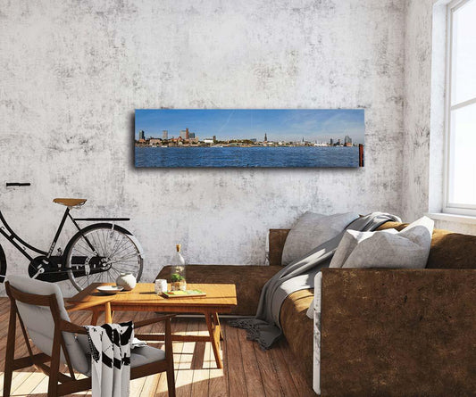 Die Hamburger Skyline vom Südufer der Elbe gesehen an einer hellen Wand hinter einem Sofa hängend