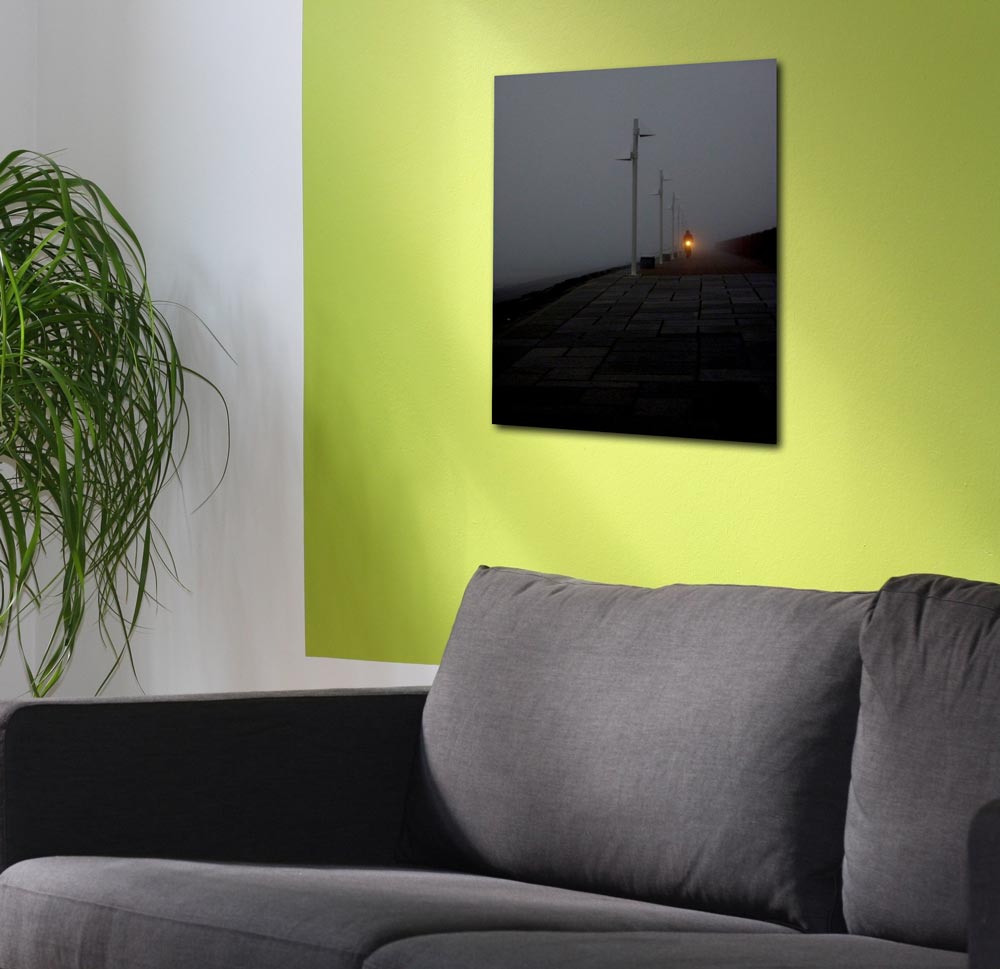 EIn Foto der Insel Norderney bei Nacht, nur einzelne Lampen sind zu erkennen, an einer grünen Wand hängend.