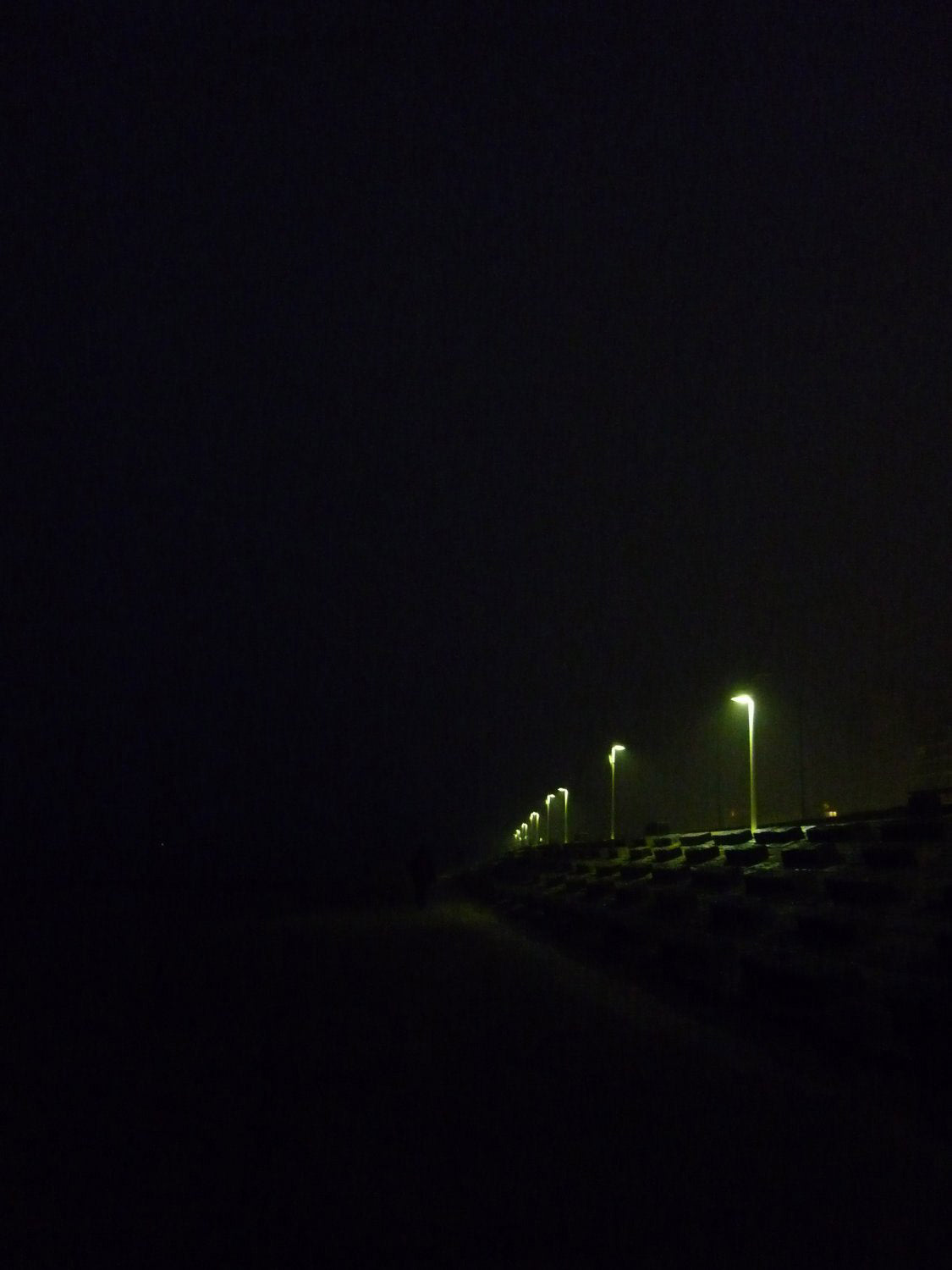 EIn Foto der Insel Norderney bei Nacht, nur einzelne Lampen sind zu erkennen.