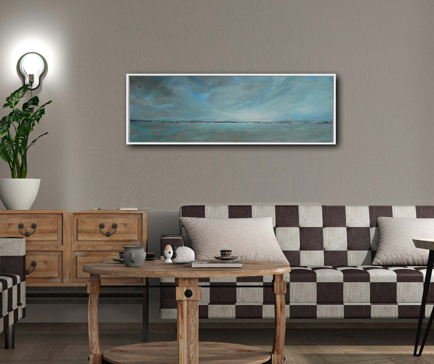 Panoramagemälde, horizont mit Bergen und wolkigem Himmel, blaugrün und beige, an beiger Wand hängend mit kariertem Sofa