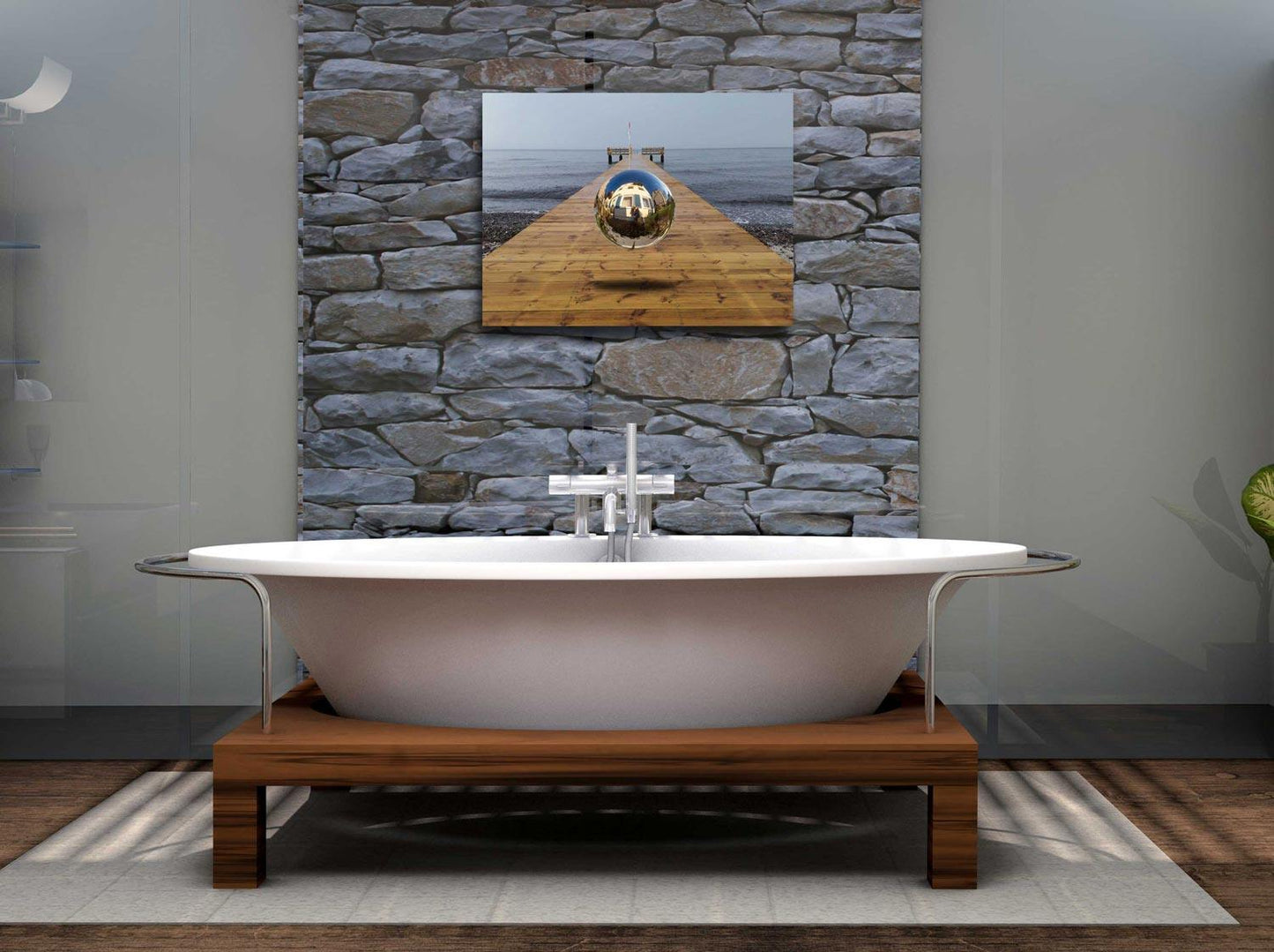 Eine Kugel schwebt über einem Steg der in die Ostsee führt-Surreales Werk, an einer Steinwand über eine Badewanne hängend.
