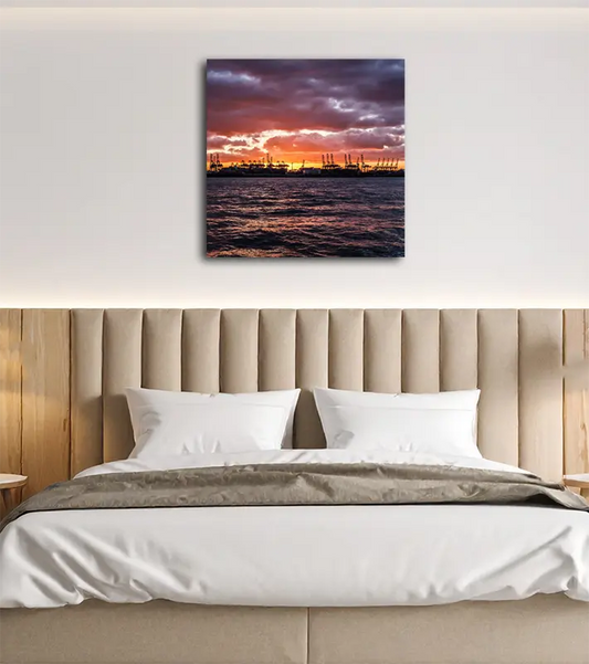 Farbfoto, orangefarbener Himmel, Hafenkräne im Schattenriss heben sich dunkel vor dem hellen Himmel ab, in einem Schlafzimmer an heller Wand hängend