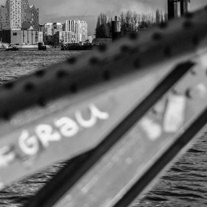 Schwarz weiß Foto über die Elbe, im Hintergrund die Elbphilharmonie und HTC, im Vordergrund ein unscharfer Brückenpfeiler, detail des unscharfen Brückenpfeilers