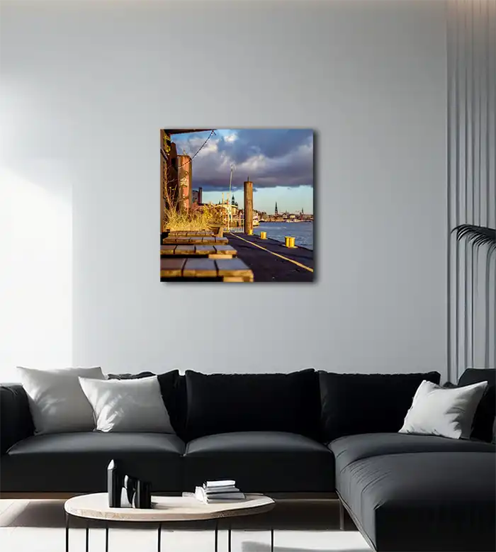 Farbfoto vom Anleger hinter der Fischauktionshalle mit Kirchen und gelben Pollern, an heller Wand mit dunklem Sofa