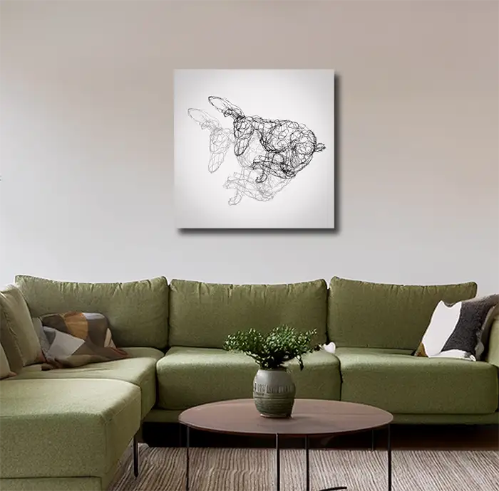 Fineart Print der Drahtfigur eines rennenden Hasen mit Schatten  vor hellem Hintergrund, an heller Wand mit grünem sofa