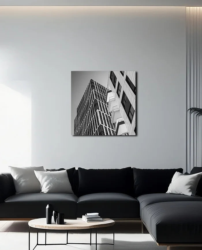 Schwarz weiß Fotografie moderner nach oben strebender Architektur geprägt von Linien und Kanten, an heller Wand hängend mit dunklem Sofa