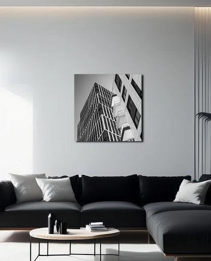 Schwarz weiß Fotografie moderner nach oben strebender Architektur geprägt von Linien und Kanten, an heller Wand hängend mit dunklem Sofa