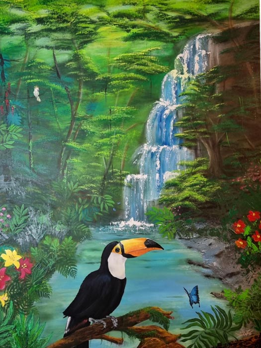 Das Acrylgemälde "Toucan in the jungle" der Künstlerin Sara Schubert zeigt eine Landschaft mit Wasserfall. Mittig verweilt ein Toucan auf einem Ast. 120x90 cm